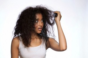 Young woman holding hair against white background